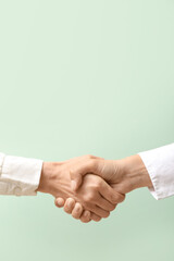 Businesswomen shaking hands on color background