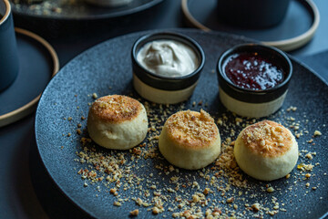 cottage cheese cheesecake in a black plate with sour cream and jam