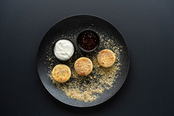 cottage cheese cheesecake in a black plate with sour cream and jam