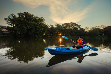 Kayaking water sports with copy space. Young Kayaker man in a beautiful lake during sunrise in the morning.