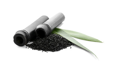 Heap of activated carbon powder and bamboo sticks on white background