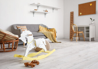 Fototapeta na wymiar Rocking horse and wooden toy cars in light child's room