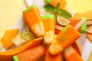 Plate with tasty popsicles and melon pieces on yellow background