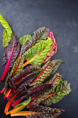 Roher bunter Mangold angeboten als close-up auf einem rustikalen schwarzen Board