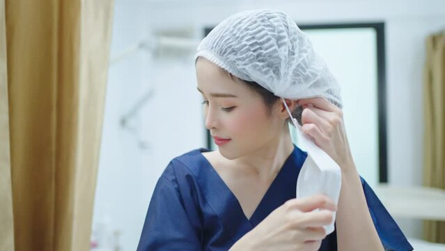 Asian Nurse with protecting costume putting mask on face standing in front of camera in hospital.Ready to receive patients in hospital. Health care, medical concept.