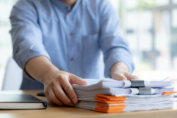 The office worker is working at the company, he is tidying up the paperwork on his desk to start...