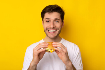 Smiling Young Guy Holding Burger At Studio