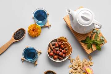 Composition with cups of blue tea, nuts and dried fruits on light background