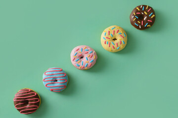 Different sweet donuts on color background