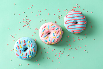 Fototapeta na wymiar Sweet donuts and sprinkles on color background