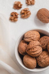 White round bowl with whole walnuts on a white background. Healthy plant food concept.