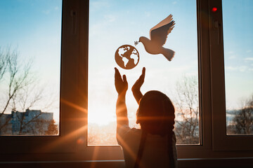child stretches his hands sunlight outside window flying dove world with branch forces globe....