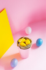 Yellow easter eggs in the pink bucket. Easter eggs in a nest on a pink-yellow background. Copy space