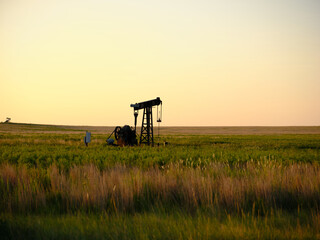 Kansas oil well in a empty field at sunset