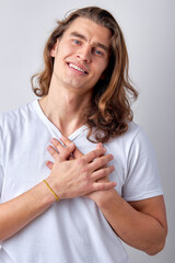 Happy smiling caucasian guy expressing gratitude, thankful for everything, keep hands on chest and looking at camera, isolated over light gray background. portrait. copy space. human emotions