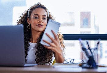 Just heard a beep, must be more good news. Shot of a young businesswoman using a cellphone while...