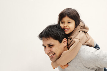 Obraz premium Portrait of excited little girl sitting on her back, young father playing together at home, happy loving dad feeling playful, continuing happy little daughter, family weekend concept