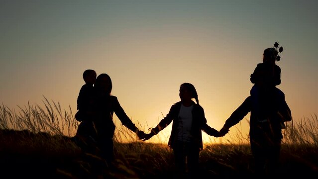 Silhouette of happy family at sunset.Family walk in park on grass.Picnic on vacation.Child with dream toy.Sunset in field. Family picnic vacation concept.Happy child with parents.Children play in park