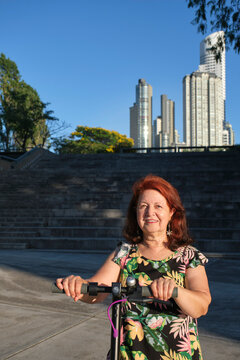 Latin Mature Woman Smiling With Her Electric Kick Scooter, Green Mobility