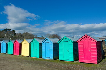 Fototapeta na wymiar Iconic, traditional beach huts. Typical British seaside scene at Abersoch, north Wales on a sunny spring day.