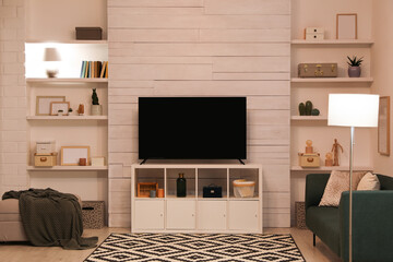 Modern TV on cabinet, comfortable sofa and decor elements in living room