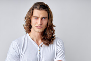 caucasian man with long hair is skeptic and nervous, disapproving expression on face. Negative person in casual white t-shirt, posing at camera. human emotions concept. isolated whitebackground