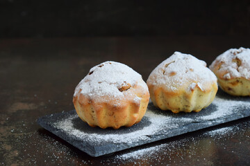 Sweet muffin from gluten free flour and walnut, sprinkled with sugar powder. Homemade baking. Organic healthy vegetarian food. Dairy free pastries. Cupcakes on a dark background. Copy space