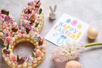 Beautiful cake, painted eggs, bunny, flowers and greeting card for Easter celebration on light background, closeup