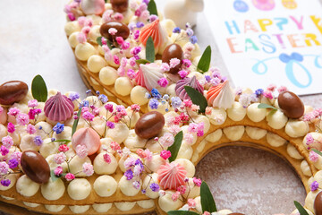 Beautiful cake and greeting card for Easter celebration on light background, closeup