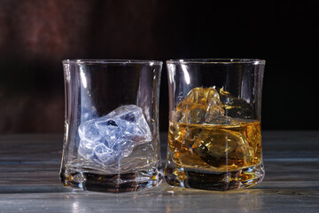 Glass of amber scotch whiskey and ice on a dark background