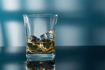 Glass of amber scotch whiskey and ice on a dark background