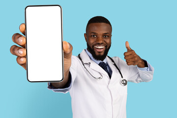 Joyful Black Doctor Demonstrating Blank Smartphone And Showing Thumb Up At Camera - obrazy, fototapety, plakaty