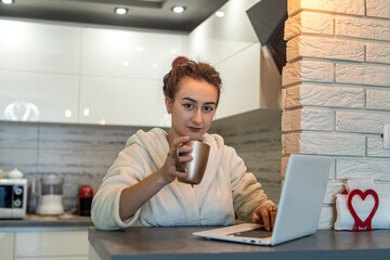 girl woke up in drinking coffee in the kitchen and working remotely during a pandemic.
