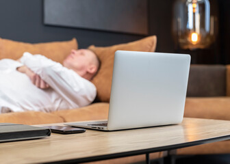 Fototapeta premium Exhausted tired businessman lying on sofa in office, relaxing after hard work day. Overtime work, overload and burnout concept. High quality photo