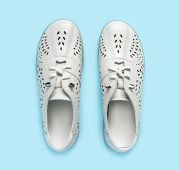 Pale white female shoes on blue backdrop. Flat lay, top view trendy fashion feminine background.