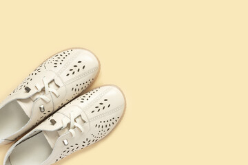 Pale white female shoes on yellow backdrop. Flat lay, top view trendy fashion feminine background.