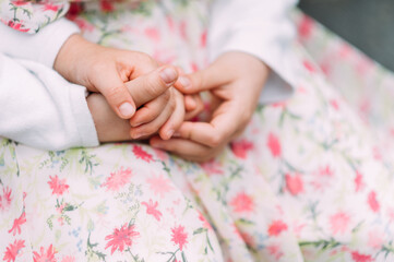kleine Hände eines Kindes im Schutz der Mutter pastellfarben