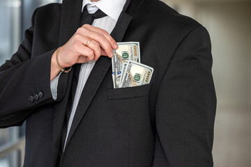 Young man in suit putting dollar bills in his pocket