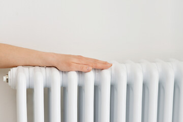 Girl warms up the frozen hands above hot radiator, close up view