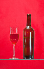On a red background, you can see a half-full wine bottle and a beautiful glass filled with wine