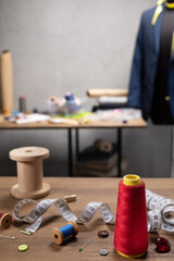 Thread spool and tape measure with sewing tools on table. Concept of clothes atelier workplace