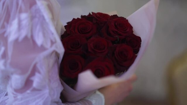 a large bouquet of red roses in the hand of a girl at a party