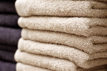 Fototapeta na wymiar Stack of terry towels, selective focus. Beige and dark bath towel closeup