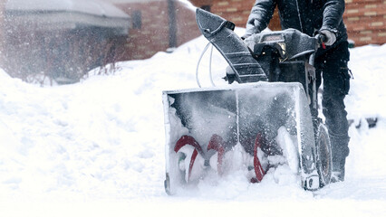 a janitor on a snowplow removes snow in the courtyard of a residential building