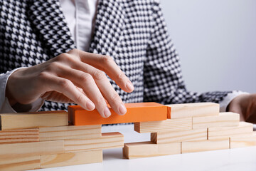 Businesswoman building bridge with wooden blocks at table, closeup. Connection, relationships and deal concept
