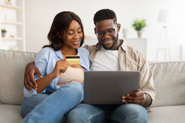 Fototapeta premium Black couple using pc and debit credit card at home