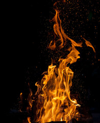 Orange flames of fire on a black background of the night. Blurred background.