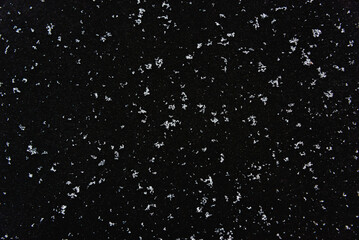 White snow on a black background. It snows at night.