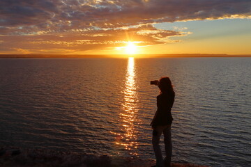 Sunset over the sea with the silhouette of a woman