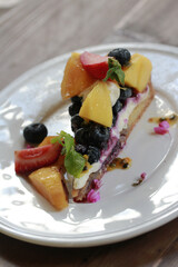 Fresh fruit tart  in white plate on wooden table